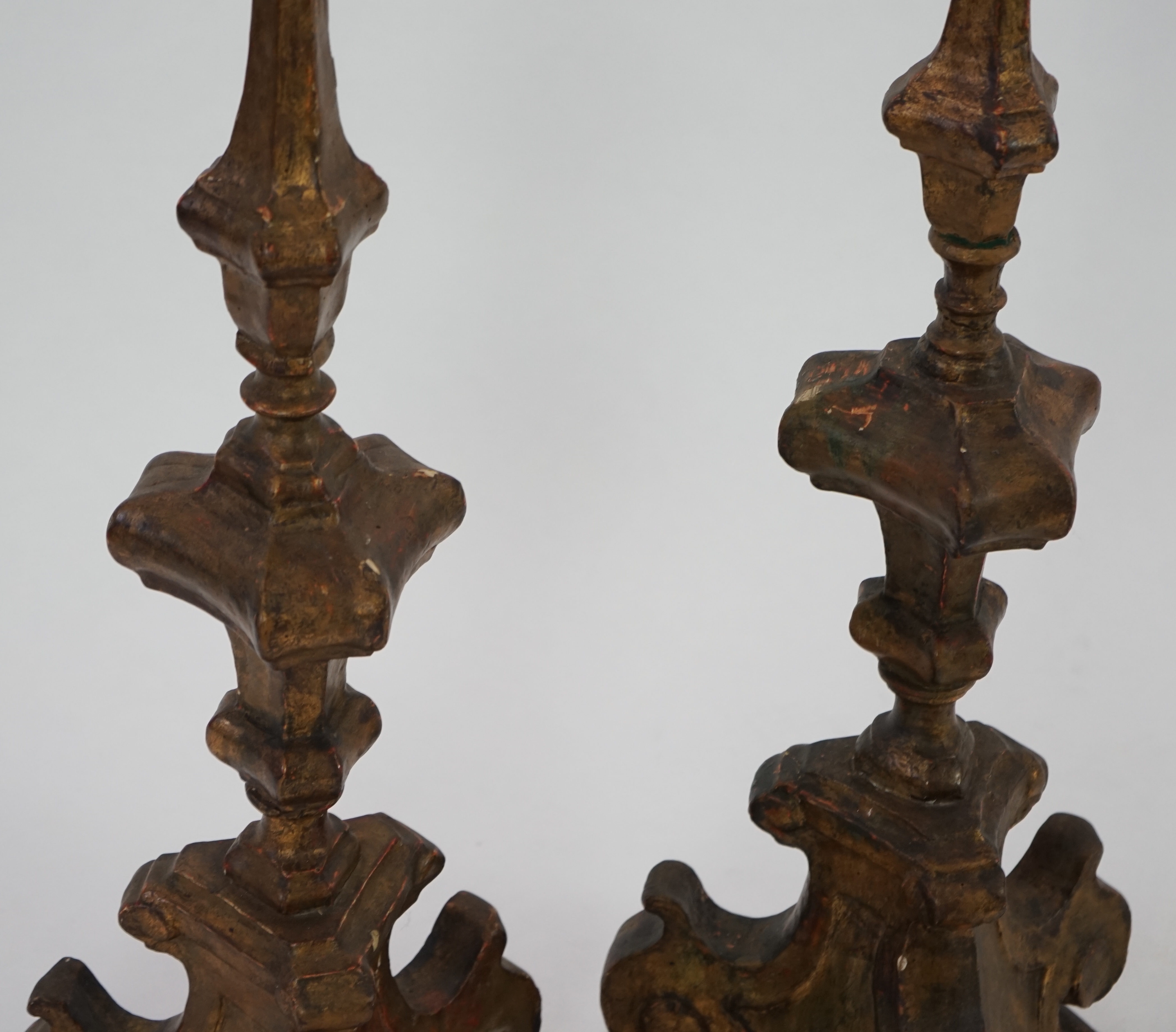 A pair of 18th century Italian giltwood candlesticks with knopped triangular stems and scroll feet, 89cm high. Condition - fair, Provenance- Brede Place, East Sussex, a former residence of the Frewen family from 1712-193